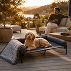 Beiges Hund auf dunkelgrauem, erhöhtem PurePet Hundebett mit Plüschpolster auf Holzterrasse.